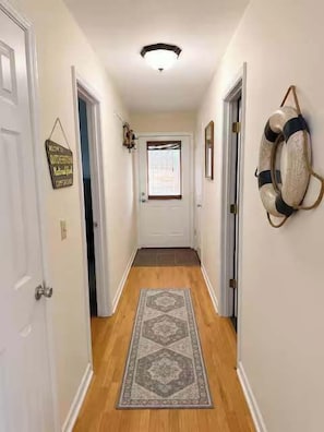 A hallway with a patterned rug, a life preserver decoration, and a welcome sign.