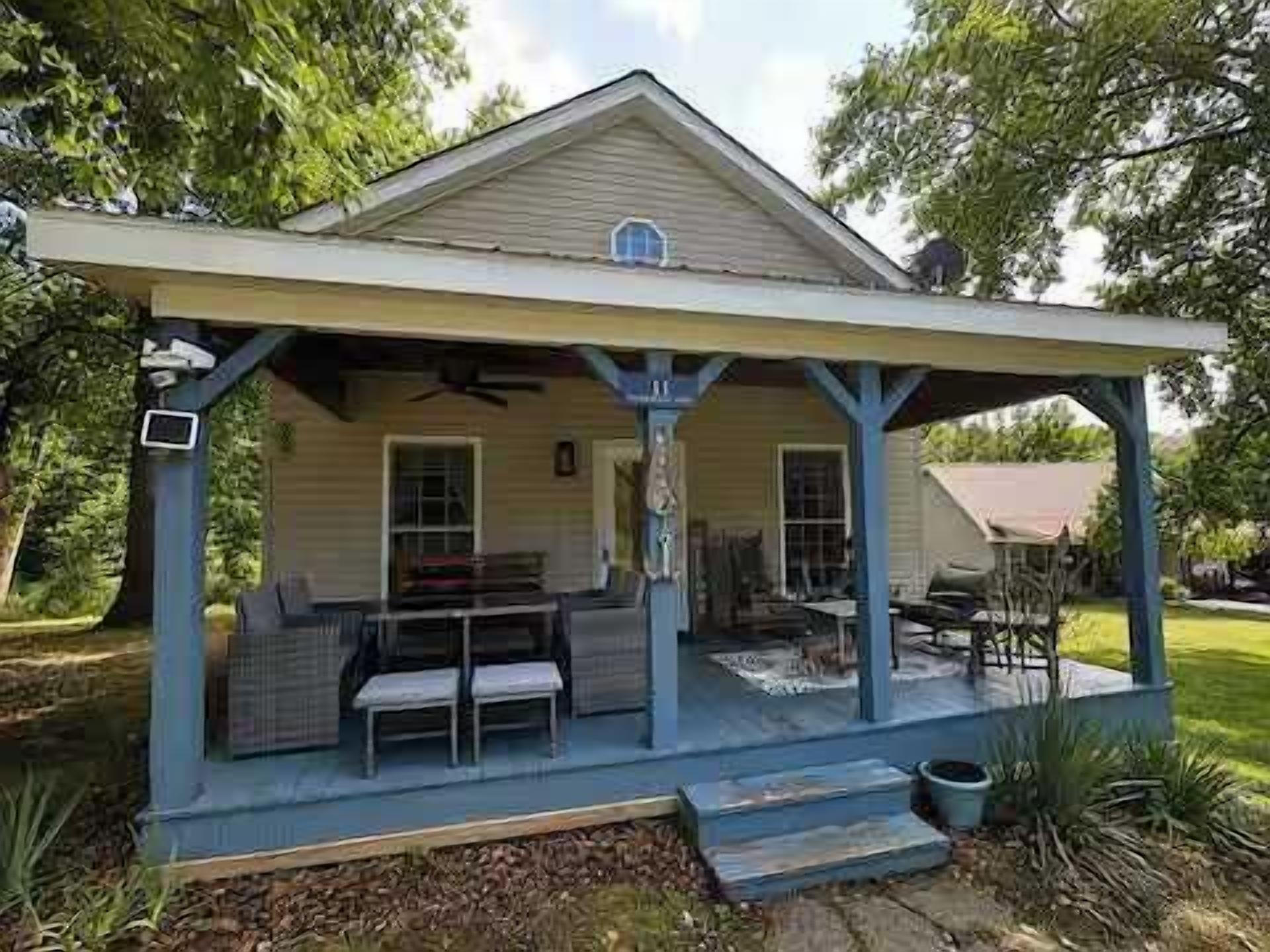 A covered porch with outdoor furniture, a small table, and a chair.