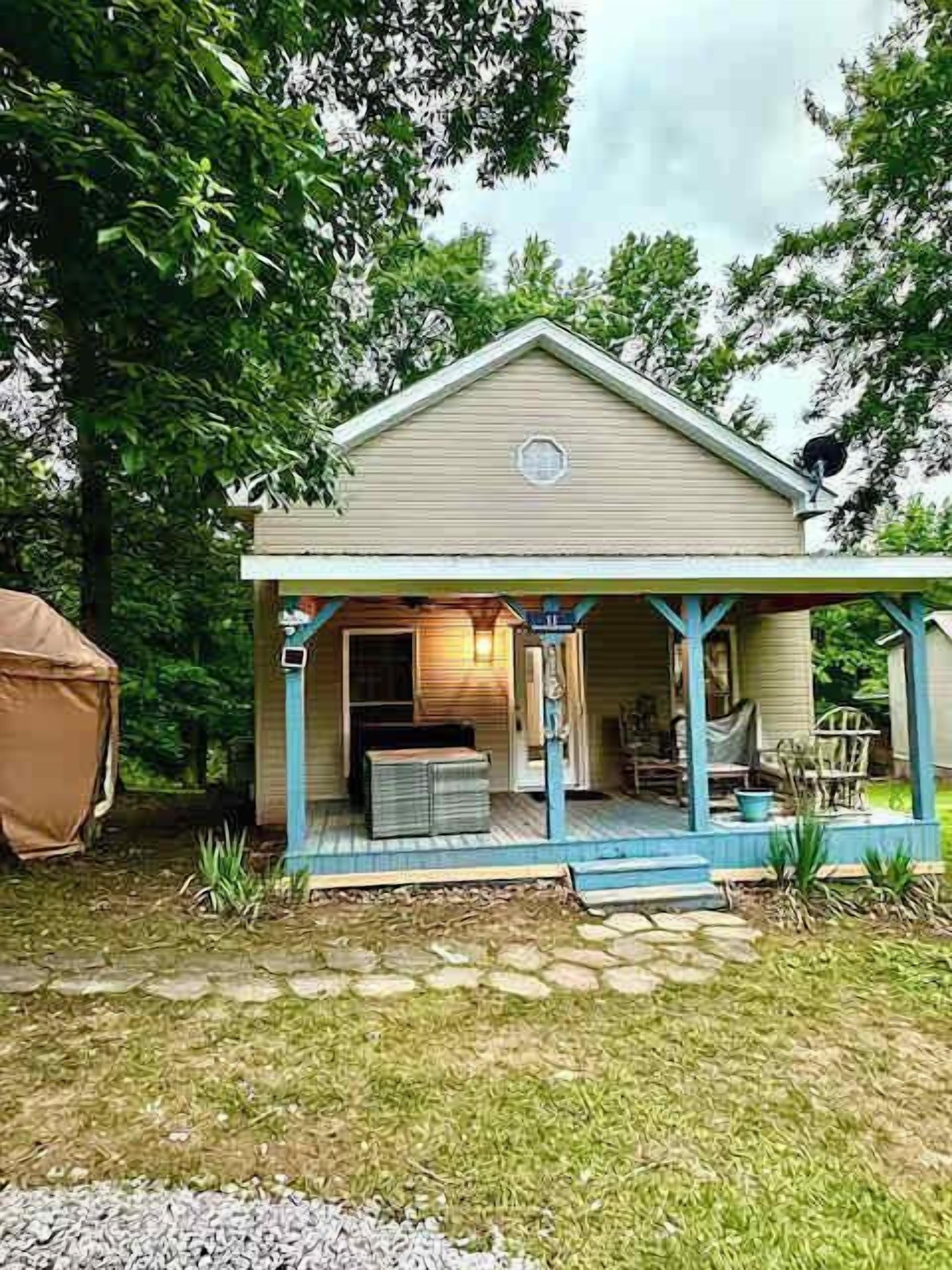 A two-story house with a porch, a covered outdoor seating area, and a small garden.