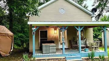 Une maison à deux étages avec un porche, un espace extérieur aménagé et couvert, et un petit jardin.