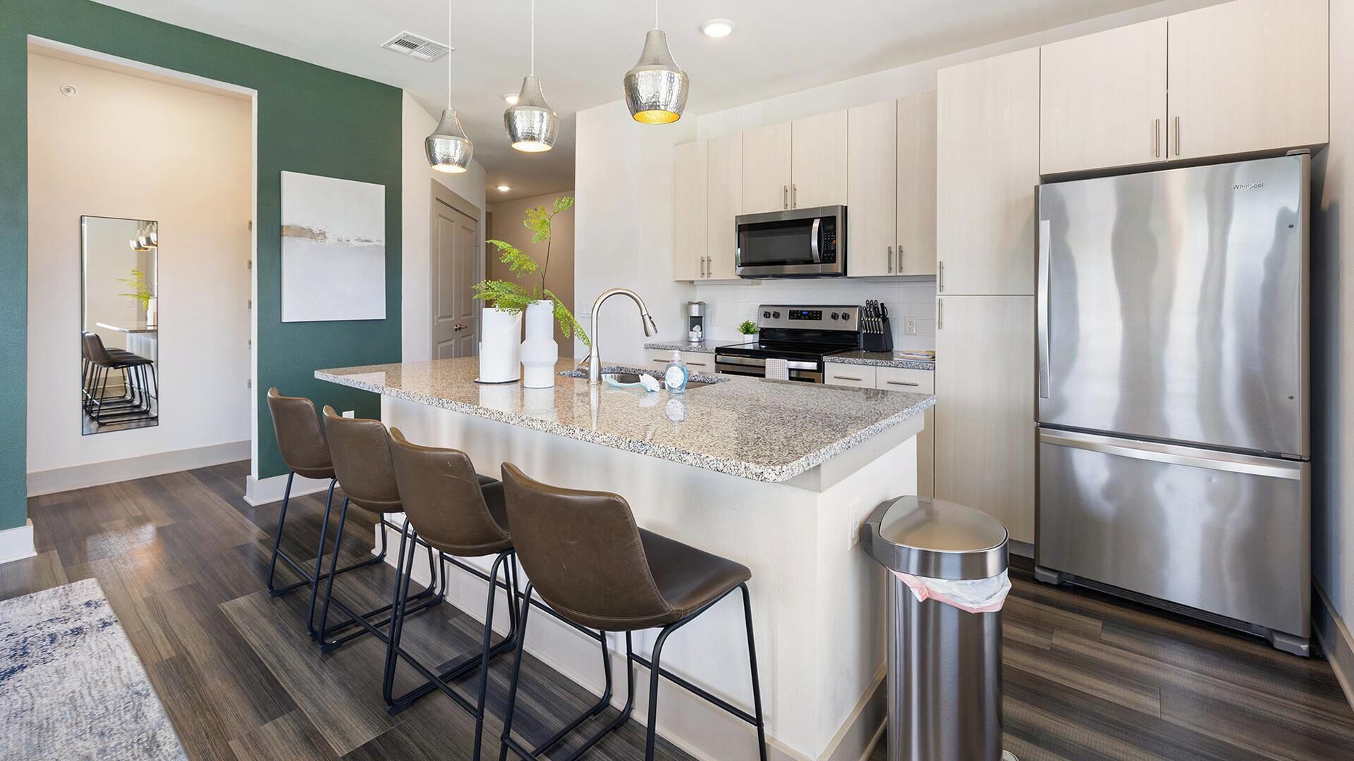 A modern kitchen with a central island, stainless steel appliances, and bar stools.