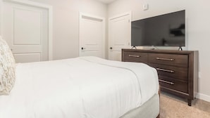 Ein Schlafzimmer mit einem Bett, einem Schminktisch, einem Fernseher und zwei Türen.