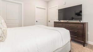 A bedroom with a bed, a dresser, a television, and two doors. - Landing Stylish 1bd, Gym (Beaufort)