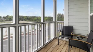 A covered porch with a view of a parking lot and trees. - Landing Stylish 1bd, Gym (Beaufort)