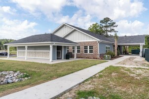 A residential house with a covered porch, a brick exterior, and a driveway.