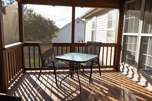 A covered outdoor area with a wooden deck, two chairs, and a table.