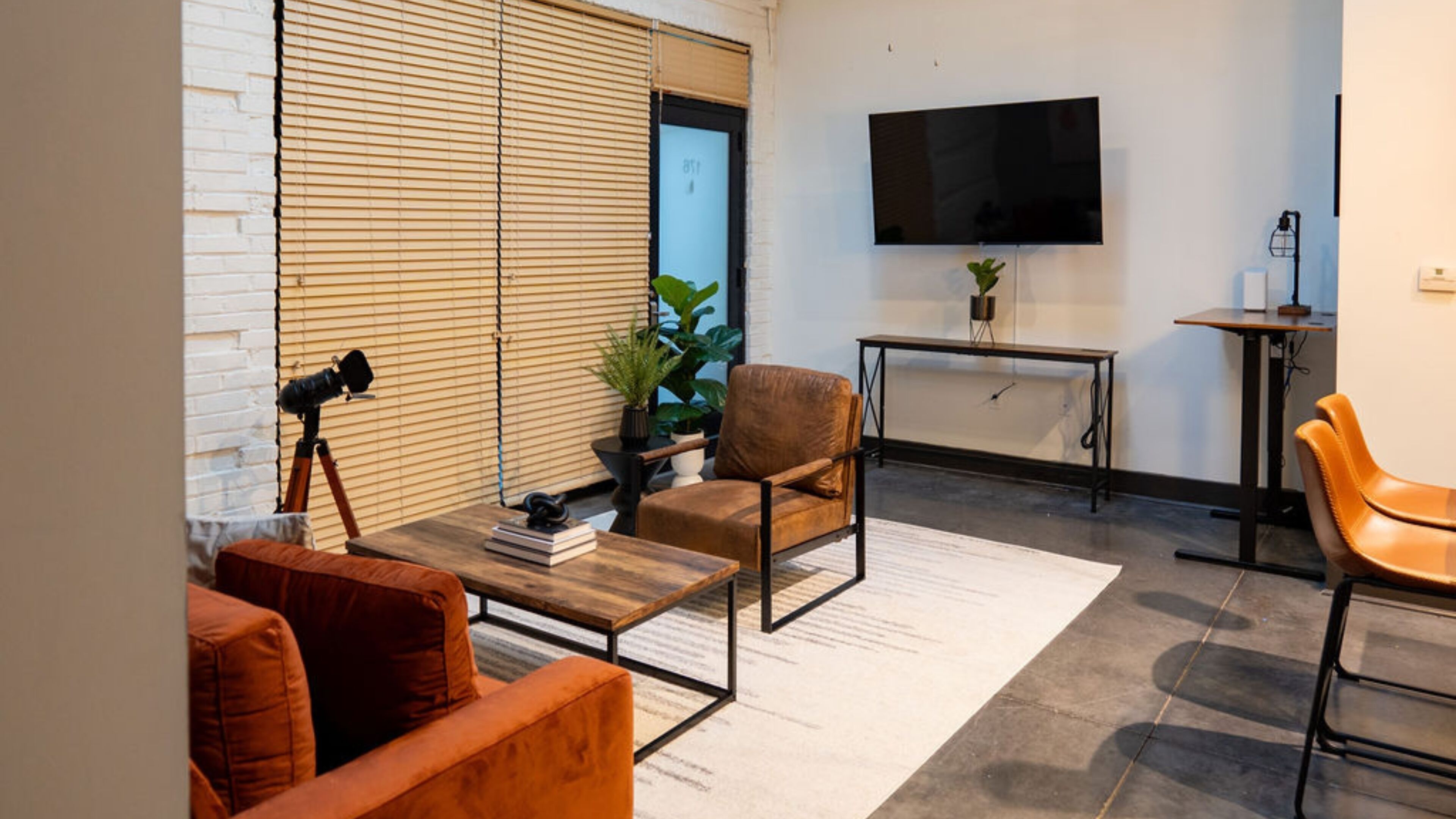 Una sala de estar moderna con sofá, sillón, mesa de centro y un televisor de pantalla plana montado en la pared.