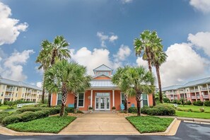 A hotel with a central entrance, surrounded by palm trees and a well-maintained lawn. - Seaside At Anastrasia A102 Go Coastal (St. Augustine)