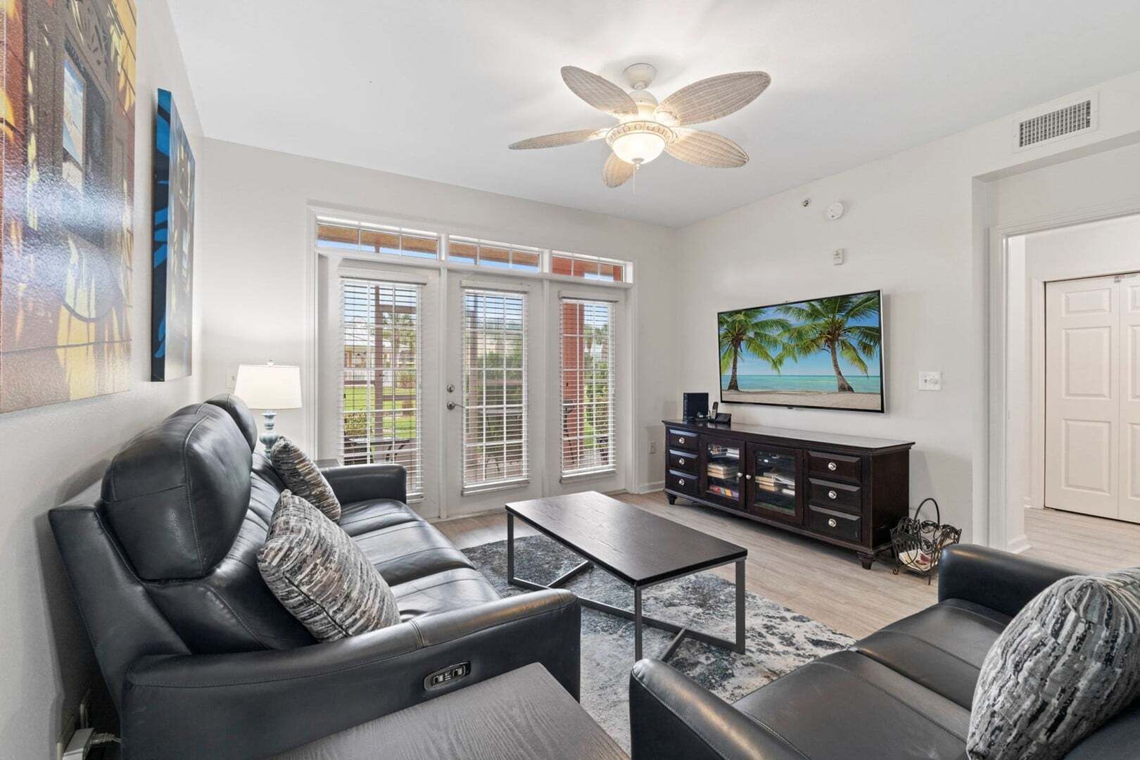 A living room with a sofa set, a coffee table, a TV, and a ceiling fan.