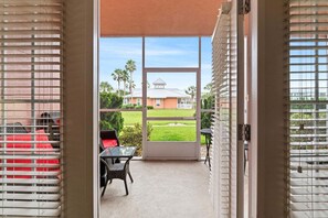 A room with a sliding glass door leading to a patio with a table and chairs. - Seaside At Anastrasia A102 Go Coastal (St. Augustine)