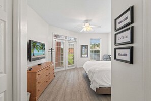 A bedroom with a bed, a dresser, a television, and a ceiling fan. - Seaside At Anastrasia A102 Go Coastal (St. Augustine)