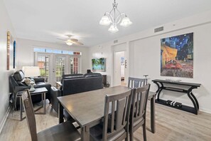 A modern living room with a dining area, a ceiling fan, and artwork on the walls. - Seaside At Anastrasia A102 Go Coastal (St. Augustine)