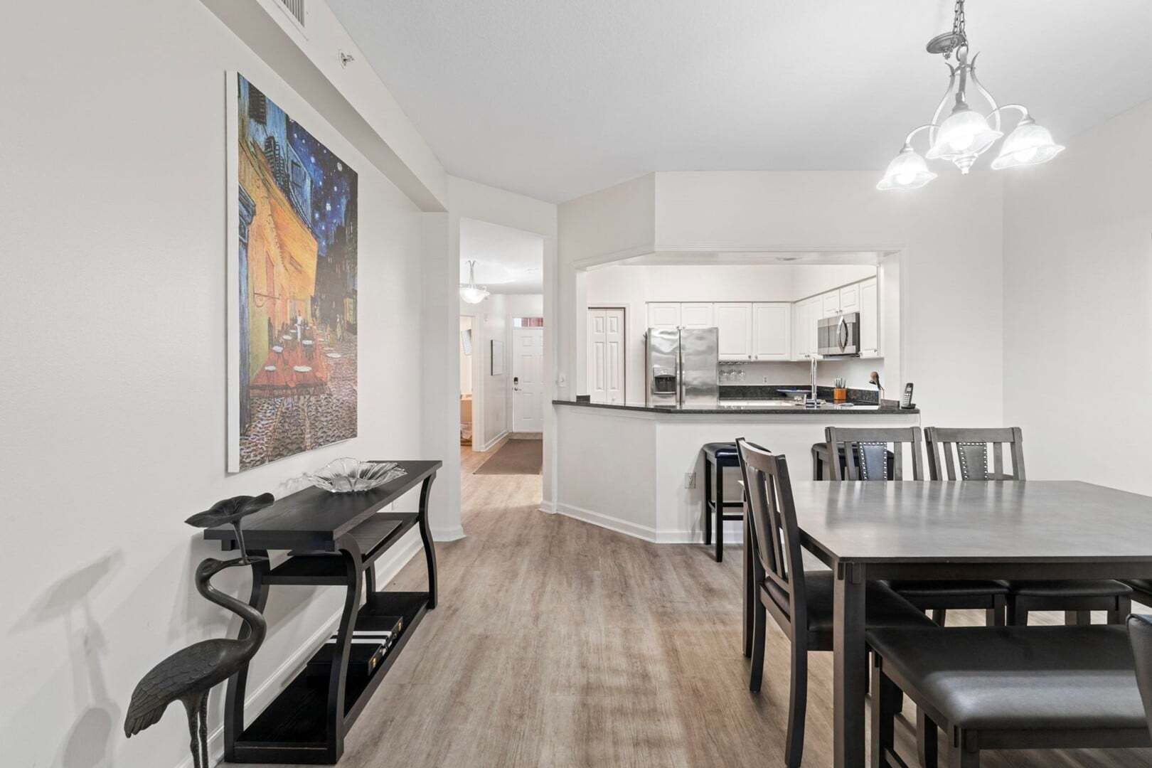 Une cuisine moderne avec des meubles blancs, un îlot central et un coin repas comprenant une table et des chaises.