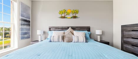 Quarto com cama grande, duas mesas de cabeceira, um criado-mudo, janela com vista e uma obra de arte na parede.