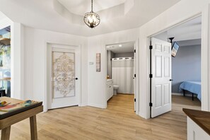 Un couloir doté d’un plancher en bois, de murs blancs et d’une porte donnant sur une salle de bain.