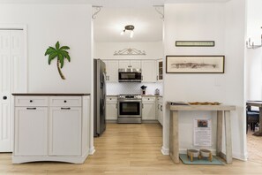 Une cuisine moderne avec des armoires blanches, des appareils en acier inoxydable et un plancher en bois.
