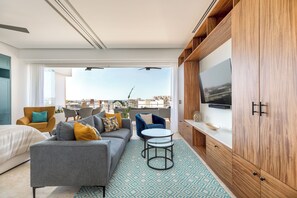 Een moderne woonkamer met een bank, stoelen, een salontafel en een tv op een houten kast.