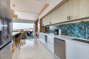 A modern kitchen with a view of the city, a dining area with a view, and a large window. - Largest Pool in Zona Romantica at SOHO PV (Puerto Vallarta)