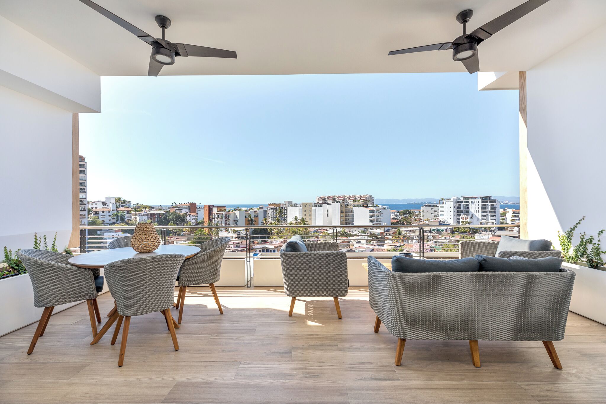 A balcony with a table and chairs, a ceiling fan, and a view of a cityscape.