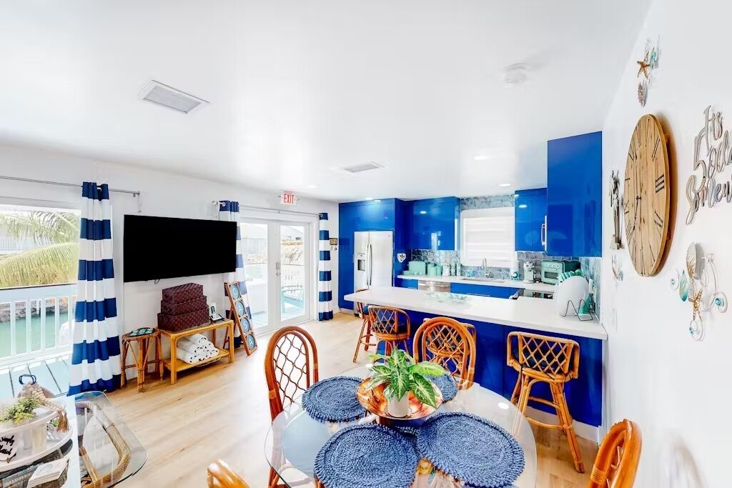 Um interior moderno com área de refeições, cozinha e uma grande janela com cortinas.