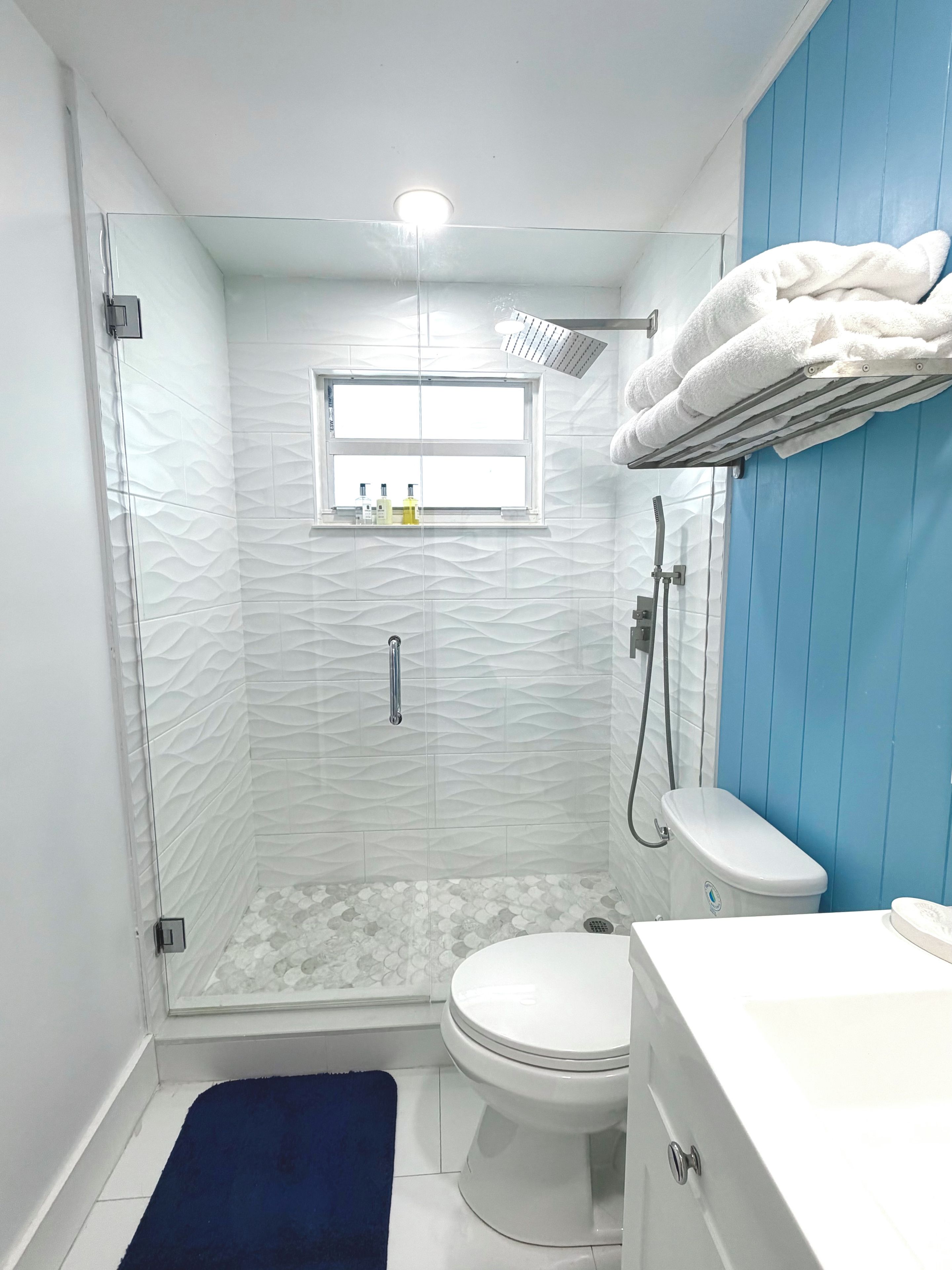Ein modernes Badezimmer mit einer Duschkabine aus Glas, einer weißen Toilette und einer blauen Wand.