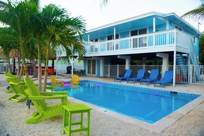 A two-story building with a pool, outdoor seating, and palm trees. - Gulf-to-Atlantic Waterfront Escape — Pool, Tiki Bar & Endless Fun (Marathon)