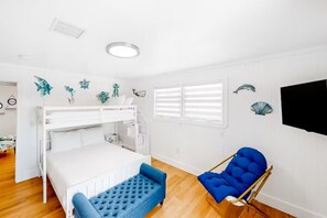 Ein Zimmer mit einem Etagenbett, einem blauen Sessel und Wanddekoration.