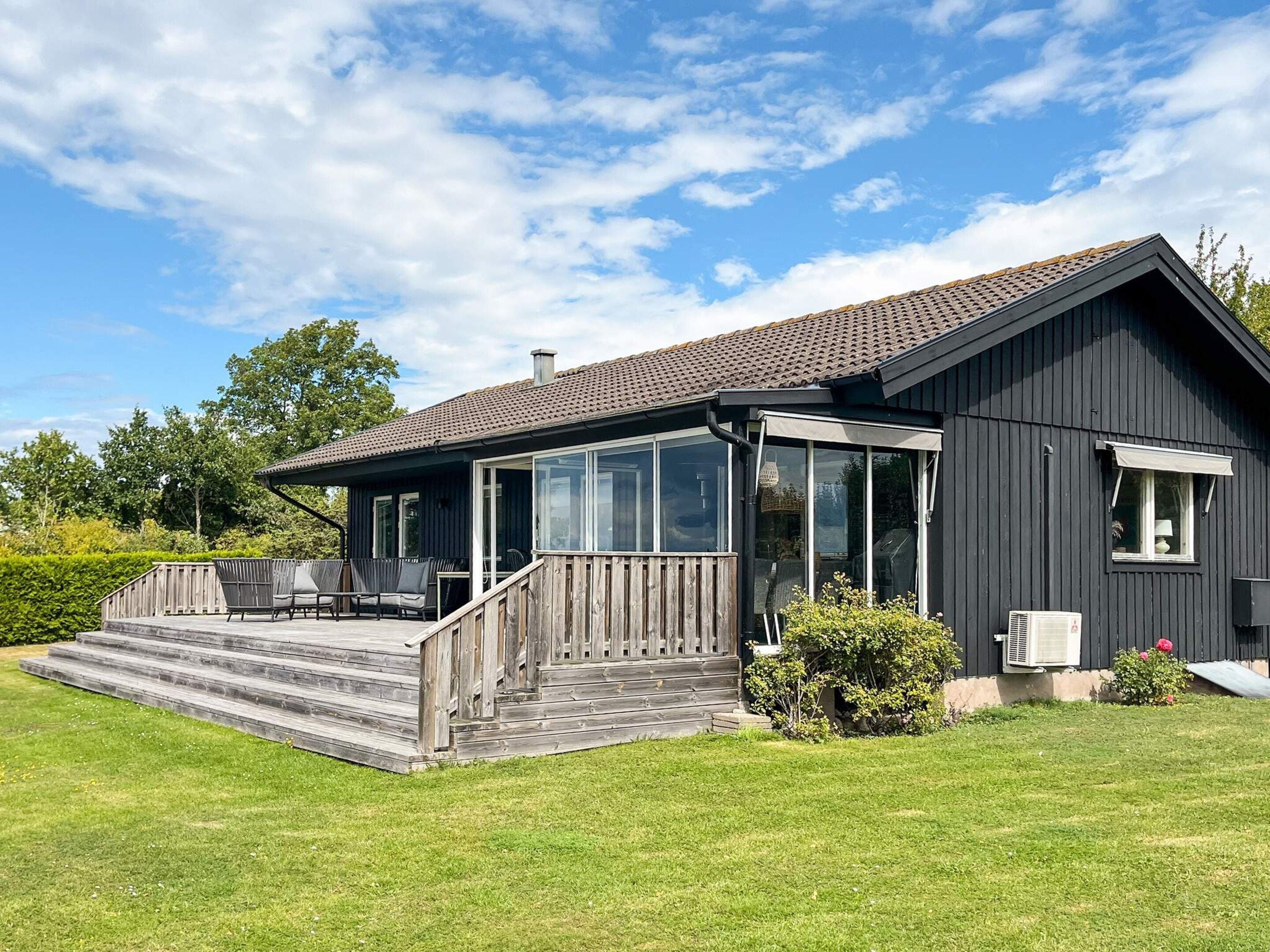A modern house with a covered patio, a large glass window, and a wooden deck.