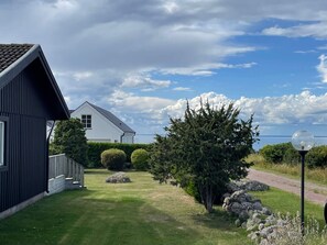 A residential property with a well-maintained lawn, a large coniferous tree, and a stone wall. - 8 Person Holiday Home in Kopingsvik (Kopingsvik)