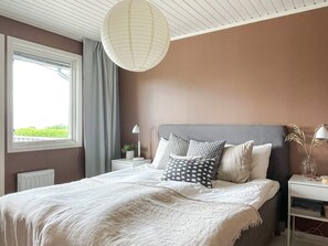A bedroom with a bed, a bedside table, a lamp, a window, and a view of greenery outside. - 8 Person Holiday Home in Kopingsvik (Kopingsvik)