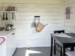A compact kitchen with white wooden walls, a stove, a sink, and a hanging basket. - 8 Person Holiday Home in Kopingsvik (Kopingsvik)