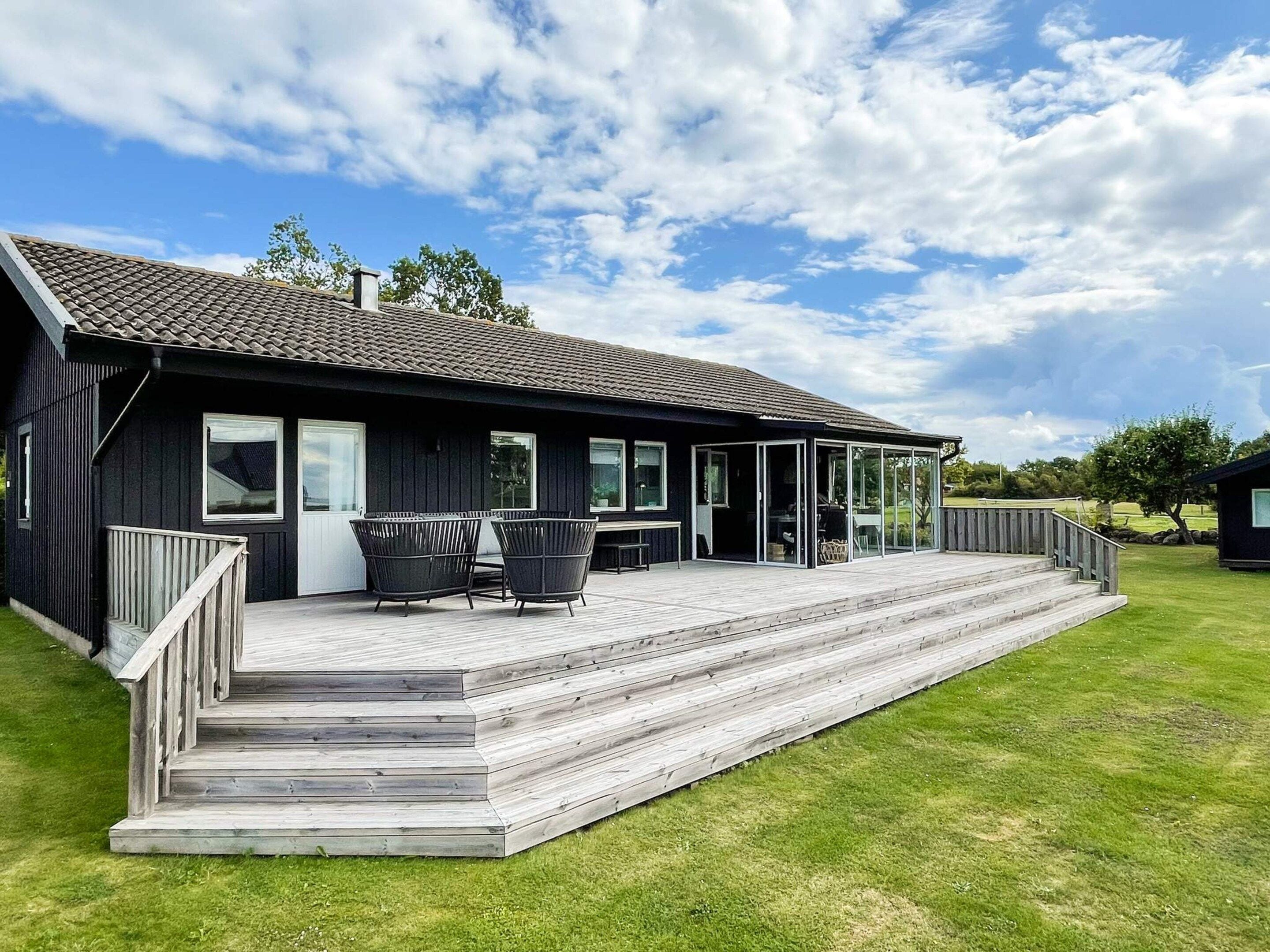 A modern black building with a covered patio area, outdoor seating, and a wooden deck.