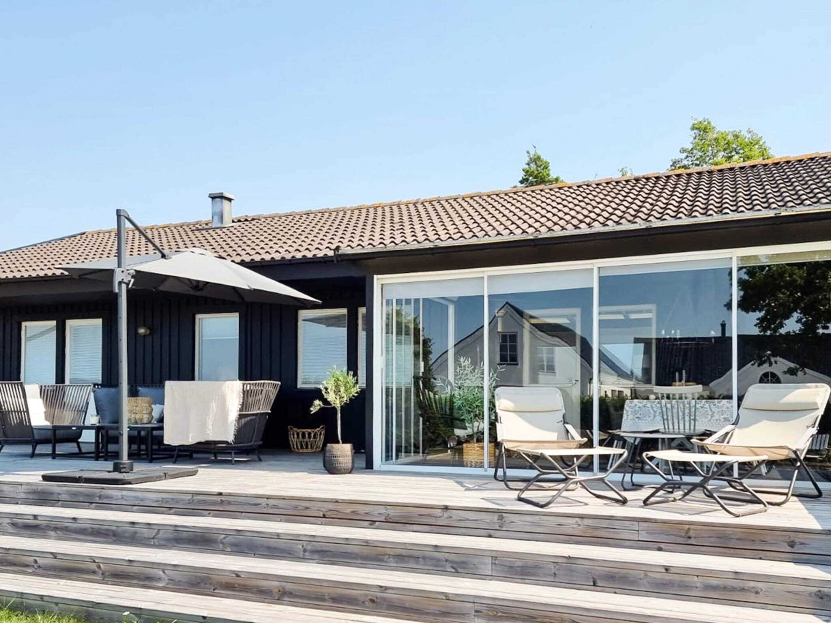 Una casa moderna amb un pati que disposa de mobiliari exterior i una porta de vidre que dona a un espai exterior cobert.