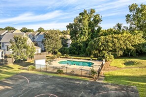 Un patio trasero residencial con piscina, un área de patio cercada y un cobertizo pequeño.