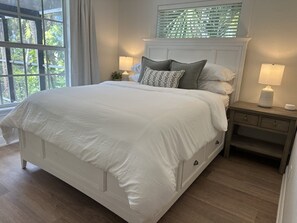 Un dormitorio con una cama grande, una mesita de noche, una lámpara y una ventana con persianas.