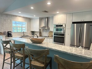 A modern kitchen with a large island, stainless steel appliances, and a view of the outdoors.