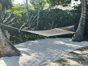 A hammock suspended between trees in a garden with a stone pathway.
