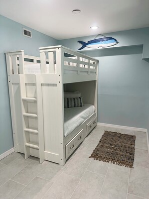 A bunk bed with a ladder, a small rug, and a ceiling fan.