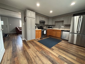A modern kitchen with wooden flooring, stainless steel appliances, and light gray cabinetry.