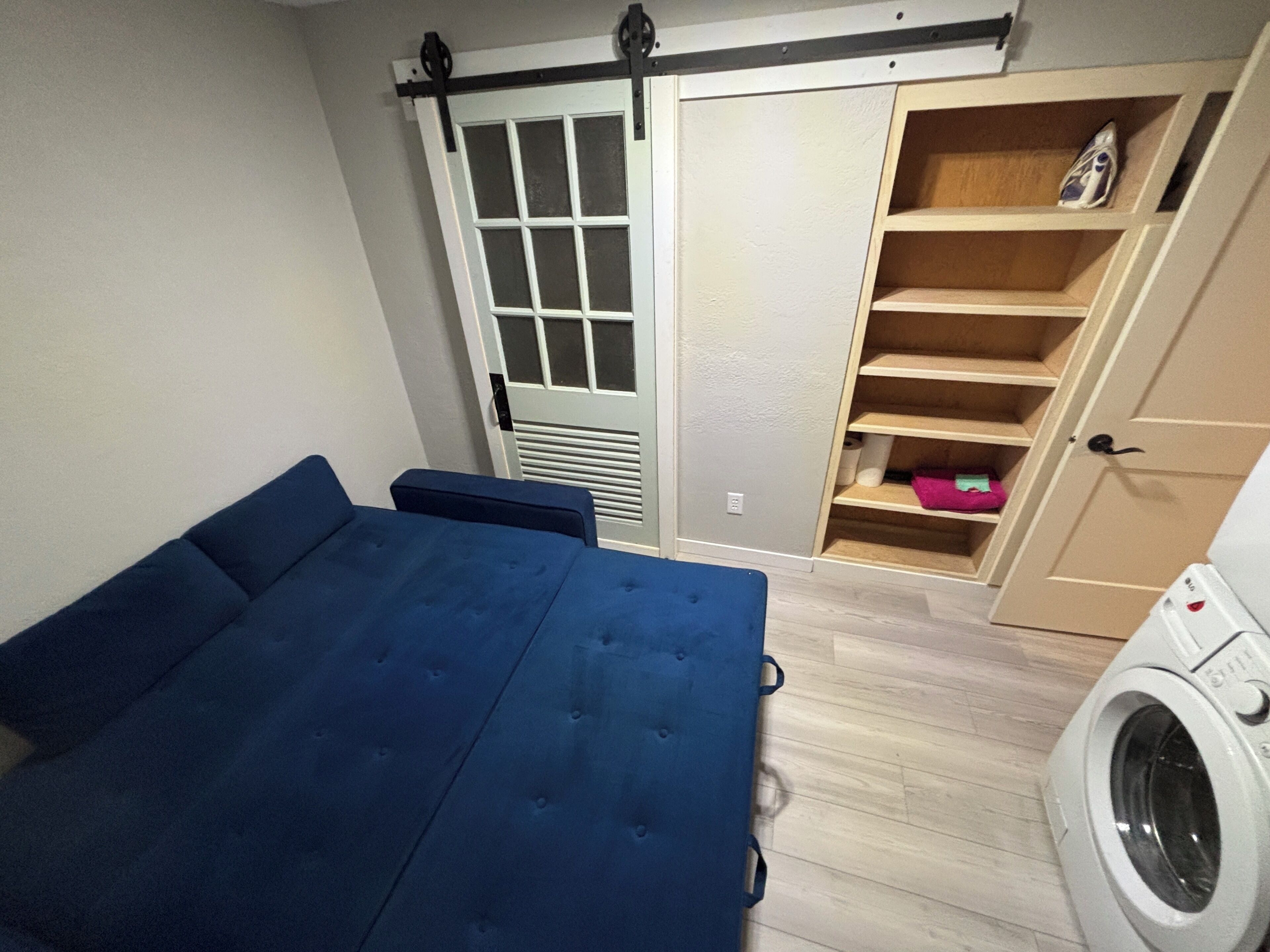 A bedroom with a bed, a wardrobe, and a washing machine.