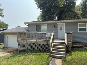 A residential house with a front deck, a garage, and a mailbox. - Boji Park Shuffle: 5-bedroom home in the middle of all the action (Arnolds Park)