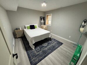 A bedroom with a bed, bedside table, nightstand, dresser, window, and a mirror. - Boji Park Shuffle: 5-bedroom home in the middle of all the action (Arnolds Park)