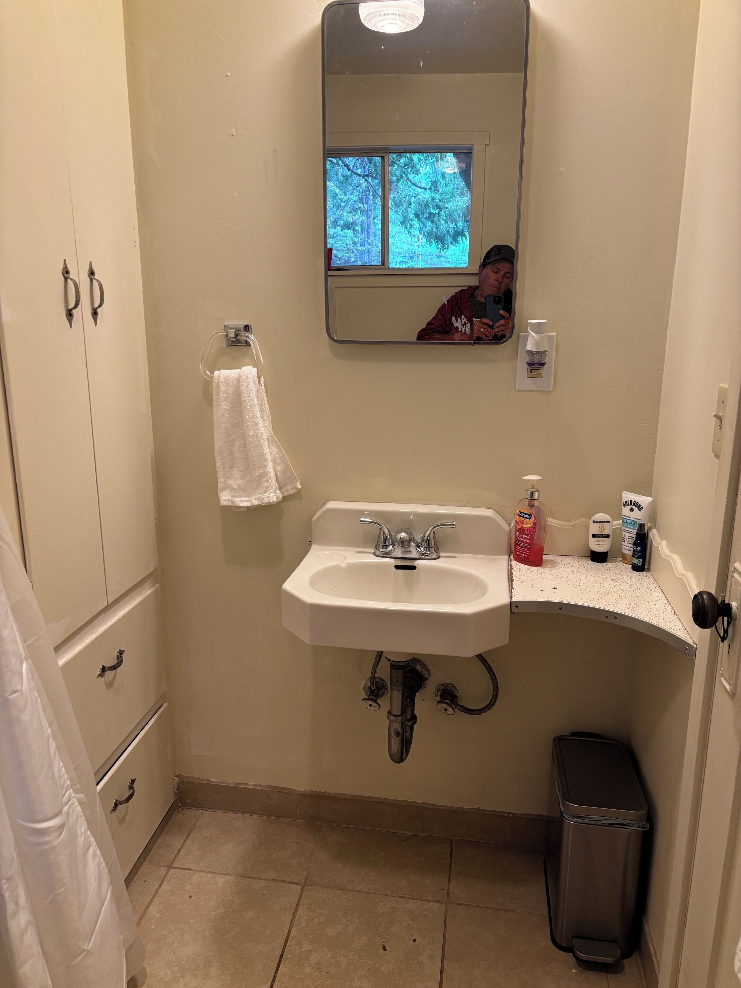 A bathroom with a sink, mirror, and a window.