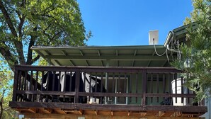 A two-story house with a balcony, a green exterior, and a visible chimney.