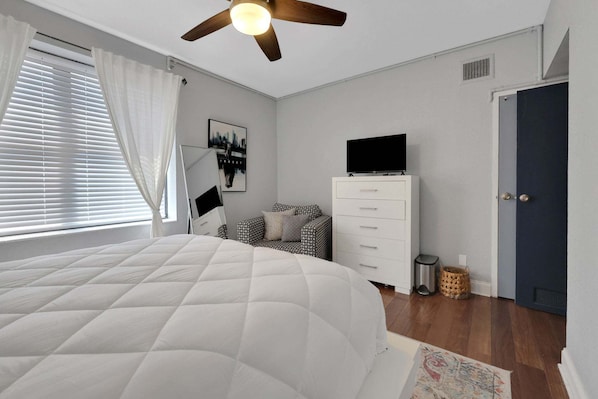 A bedroom with a bed, a dresser, a television, and a door. - Downtown Jacksonville Retreat Walk to Events & Stadium (Jacksonville)