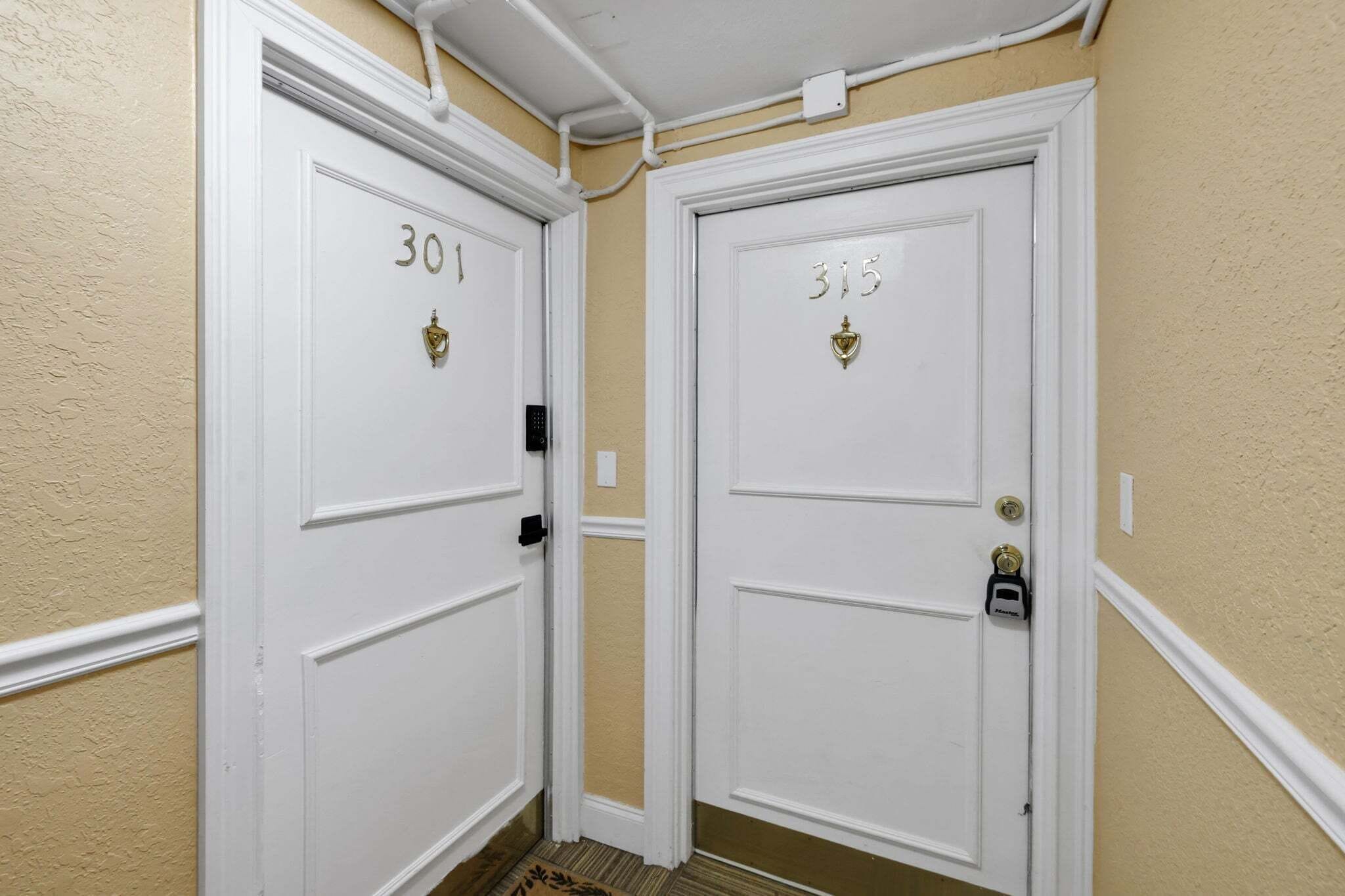 Two white doors with numbers 301 and 315, a white wall, and a beige floor.