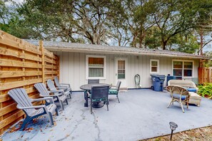 A covered patio with outdoor furniture, a trash bin, and a hose. - Breezy Bungalow Near Beach/golf With Private Patio & Updated Interior (Fernandina Beach)