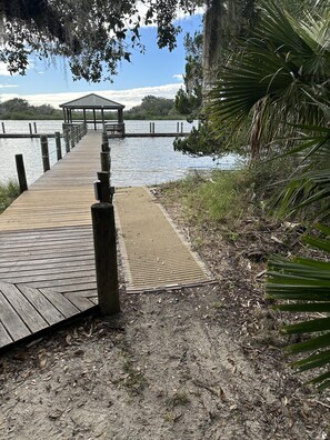A wooden dock leading to a covered pavilion by a calm body of water. - Coastal Luxury at Surf Club Direct Oceanfront Resort-style Amenities (Palm Coast)