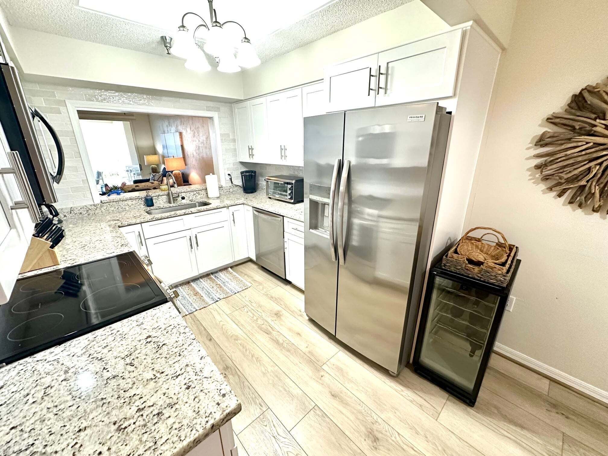 A modern kitchen with white cabinetry, stainless steel appliances, and a granite countertop.