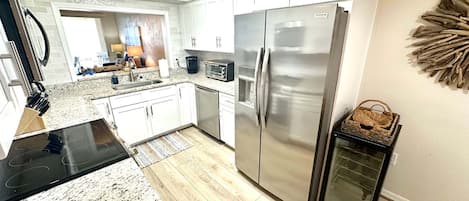 A modern kitchen with white cabinetry, stainless steel appliances, and a granite countertop.